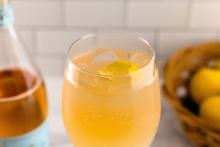 Golden cocktail with lemon twist and ice in glass, professional drink photography for Speak Easy Podcast.