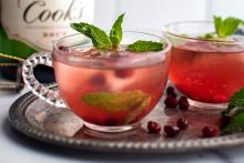 Pomegranate cranberry cocktails with fresh mint garnish on silver tray, holiday drink photography for Speak Easy Podcast