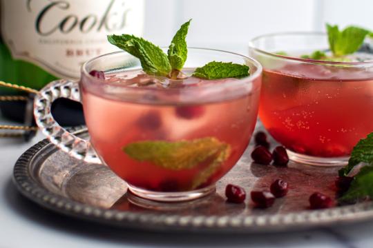 Pomegranate cranberry cocktails with fresh mint garnish on silver tray, holiday drink photography for Speak Easy Podcast