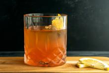 A short round glass filled with amber liquid and a lemon garnish.