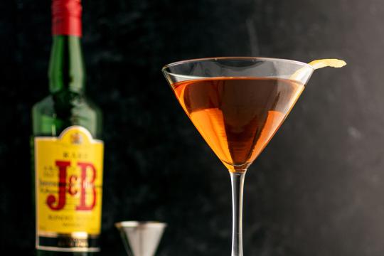 A cone shaped martini glass filled with scotch, a brown liquid