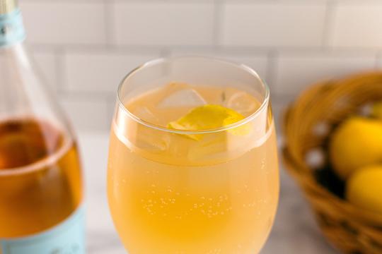 Golden cocktail with lemon twist and ice in glass, professional drink photography for Speak Easy Podcast.