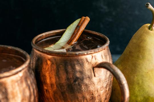 A moscow mule mug holds the Spiced Pear Gin Mule with a pear garnish.