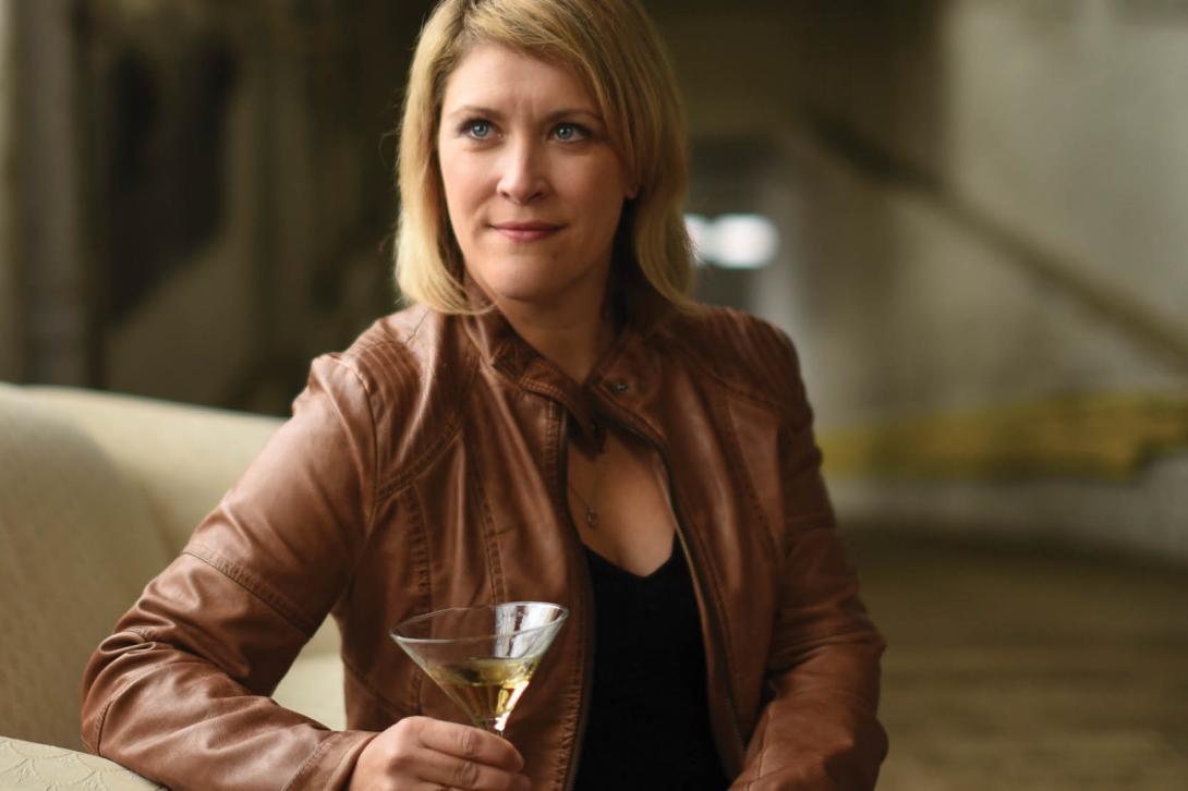 Karen, co-host of Speak Easy Podcast, holding martini glass in brown leather jacket, lifestyle portrait photography.